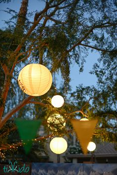 several paper lanterns hanging from a tree in the night sky, with text overlay