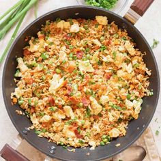 a pan filled with rice and vegetables on top of a table next to green beans