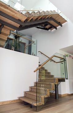 a stair case with glass railing and wooden handrails in a modern style home