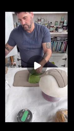 a man is making something out of clay and paper maching it on a table