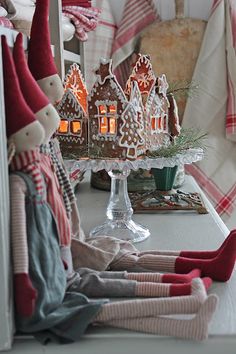 several gingerbread houses on a table with candles in the middle and elf hats hanging from them