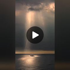 a boat floating on top of the ocean under a cloudy sky with sunbeams