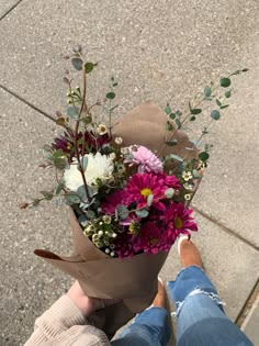 a person holding a bouquet of flowers on the sidewalk