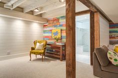 a living room filled with furniture next to a wall covered in colorful pictures and paintings