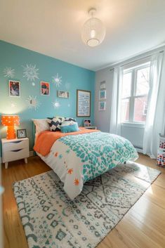 a bedroom decorated in blue and orange with snowflakes on the wall above the bed