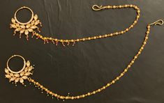 two gold necklaces with matching earrings on a black surface, one in the shape of a flower