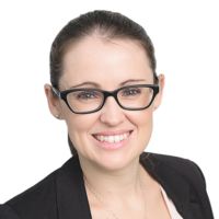 a woman with glasses smiling for the camera in front of a white background wearing a black blazer