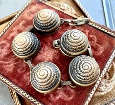 four antique buttons sitting on top of a velvet box