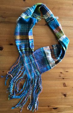 a blue and green plaid scarf laying on top of a wooden floor