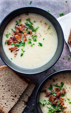 two bowls of soup with bread on the side