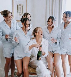 a group of women standing around each other holding wine bottles and champagne flutes in their hands