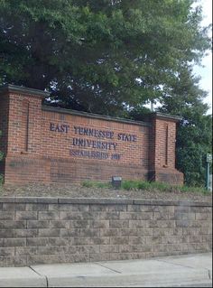 the east tennessee state university sign is shown in front of a brick wall and trees