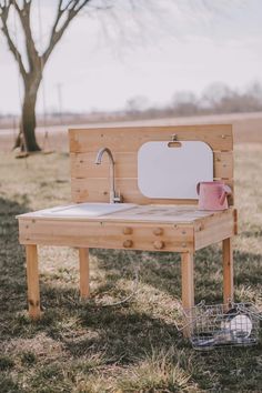 an outdoor sink made out of pallets in the grass with a tree in the background