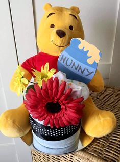 a winnie the pooh stuffed animal sitting on top of a basket filled with flowers