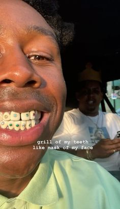 a man with braces on his teeth smiles at the camera while another man sits behind him