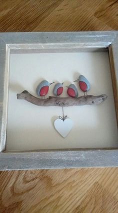 three birds sitting on a branch with a heart hanging from it's side in a shadow box