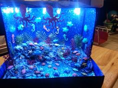 an aquarium with blue water and octopuses on it's sides, sitting on top of a wooden table