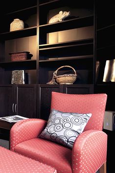 a red chair and ottoman in front of a book shelf with books on it's shelves