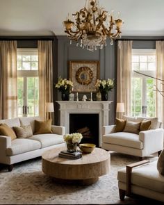 a living room filled with furniture and a chandelier hanging from the ceiling over a fire place