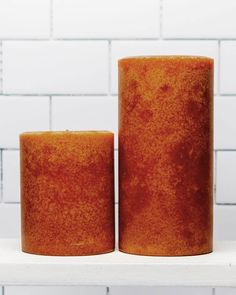 two orange candles sitting on top of a white shelf