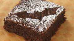 a piece of brownie sitting on top of a wooden table next to a knife