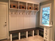 a white bench sitting under a window next to a shelf filled with bins and baskets