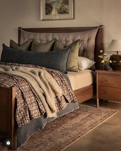 a bed with pillows and blankets on top of it in a bedroom next to a dresser