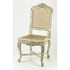 an old white chair with wicker seat and back rests against a plain background,