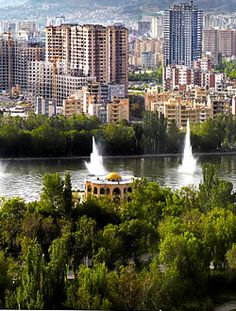 an aerial view of a city with fountains in the foreground and mountains in the background