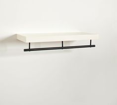 a white shelf sitting on top of a wall next to a black metal pipe holder