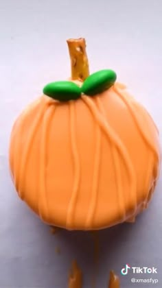 an orange cake with icing on it and a green leaf sticking out of the top