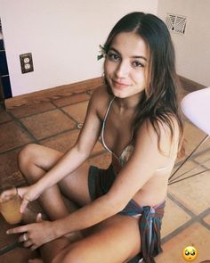 a young woman sitting on the floor holding a drink