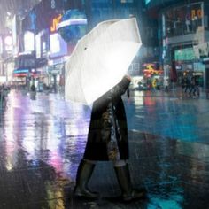 a person holding an umbrella in the rain on a city street at night with neon lights