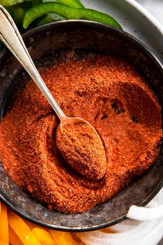 a bowl filled with spices next to green peppers