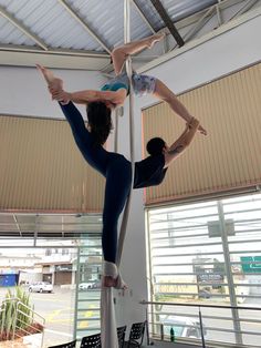 two people are doing acrobatic tricks on the pole