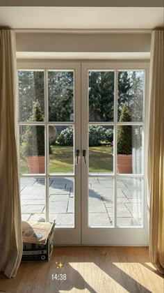 an open door leading to a patio with large windows and curtains on either side of it