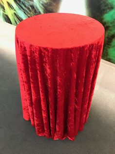 a red round table cloth sitting on top of a gray floor next to a painting