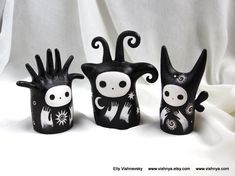 three black and white ceramic figurines sitting next to each other on a white cloth