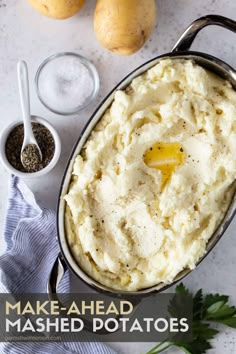 mashed potatoes in a pan with parsley and seasoning next to them on a white surface