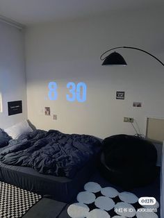 a bed room with a large bed covered in black sheets and pillows next to a wall mounted clock