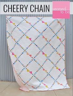 a white quilt with colorful squares on it and the words cherry chain written in black