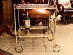 a bar cart with two bottles on it in a room full of chairs and tables