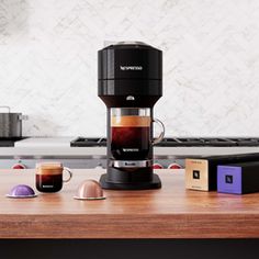 a coffee maker sitting on top of a wooden counter next to some boxes and cups