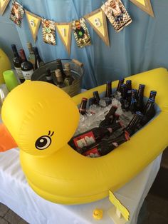 an inflatable rubber ducky filled with beer bottles on a white table cloth