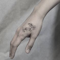 a person's hand with a flower tattoo on it