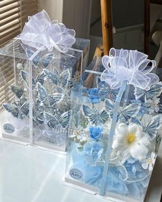 three clear boxes with blue and white flowers in them sitting on top of a table