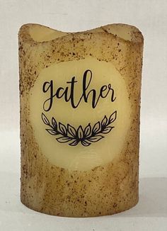 a candle with the words gather on it and an image of a plant in the middle