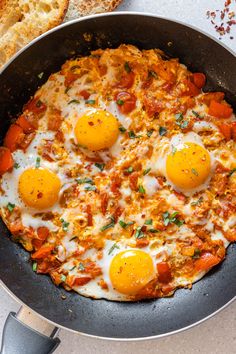 an egg and tomato pizza in a skillet with bread on the side, ready to be eaten