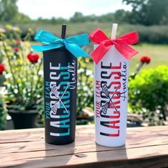 two tumbles with bows on them sitting on a wooden table in front of flowers