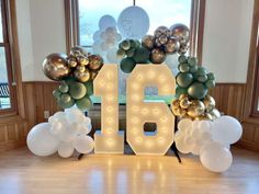 the number sixteen is surrounded by balloons and streamers in front of a large window